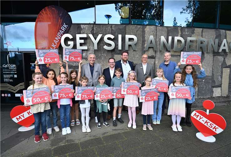 Obligatorisches Gruppenfoto vor dem Andernacher Geysir Museum mit den zwölf Gewinnerkindern des Malwettbewerbs „Geysire“ - initiiert von der Vulkanpark GmbH und der Kreissparkasse Mayen Bürgermeister Claus Peitz, der 1. Kreisbeigeordneter Pascal Badziong, Jan Scheuren als Geschäftsführer der Vulkanpark GmbH, Herbert Hürter als Leiter des KSK-BeratungsCenters am Johannesplatz sowie Torsten Lamberz freuen sich mit den Gewinnern über ihren Erfolg beim Malwettbewerb „Geysire“. Foto: KSK Mayen/Ralph Künzel