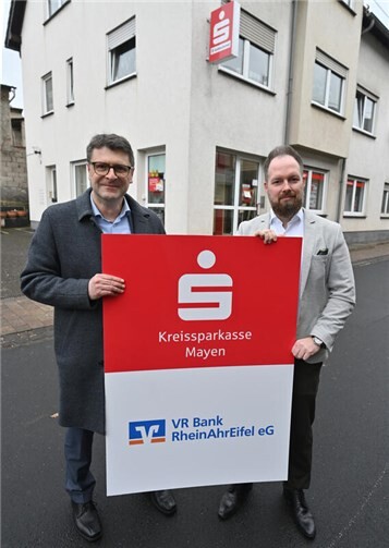 Oliver Engels, Direktor Regionalmarkt MayenMaifeldPellenz der VR Bank (links) und Stefan Weber, Vertriebsleiter Privatkunden der KSK Mayen symbolisch vor der ab April 2026 gemeinsam betriebenen SB-Filiale in der Hauptstraße 3 in Ettringen.
