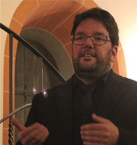 Organist Ingo Hösch erklärt vor einem der romanischen Bogen das Programm. privat