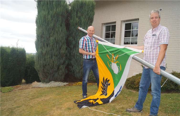 Ortsbürgermeister Heinz Zilles (links) hisste gleichnach seiner Rückkehr von der Arbeit, assistiert von Mitstreiter Ralf Lauxen,erneut die Ortsfahne. Lieg feiert seinen Erfolg, wenngleich die Schließung der Grundschule noch nicht gänzlich vom Tisch ist. Fotos: TT