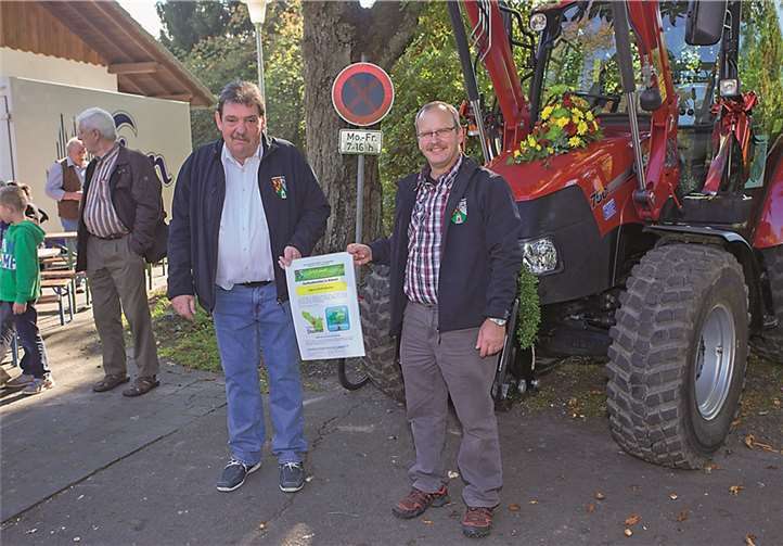 Ortsbürgermeister Wolfgang Theis (links) und Gemeindearbeiter Thomas Hering präsentieren die Logos von dem neuen Traktor.