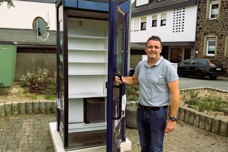 Ortsvorsteher Stefan Kneip vor dem leergeräumten Bücherschrank auf dem Dorfplatz in Miesenheim.