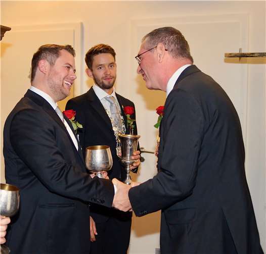 Ortsvorsteher und Schützenkönig Peter Diewald (re.) gratuliert Junggesellen-Schützenkönig Lars Angsten (li.) im Beisein von Junggesellen-Hauptmann Lukas Knieps.