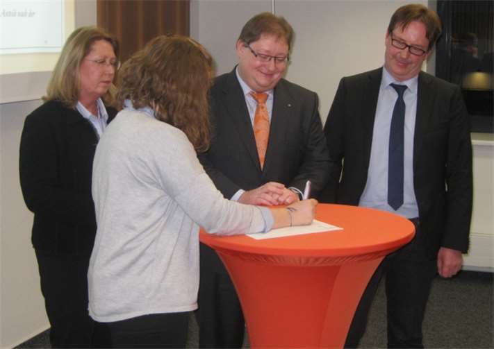 Pascale Hermann (vorne, Schülervertreterin), Christine Welker-Krumm (Schulelternbeirat), Joachim Borchert (VR-Bank) und Bernhard Geyermann (Schulleiter) unterzeichnen als erste symbolisch die Satzung und sind somit die ersten Gründungsmitglieder der neuen Schülergenossenschaft.