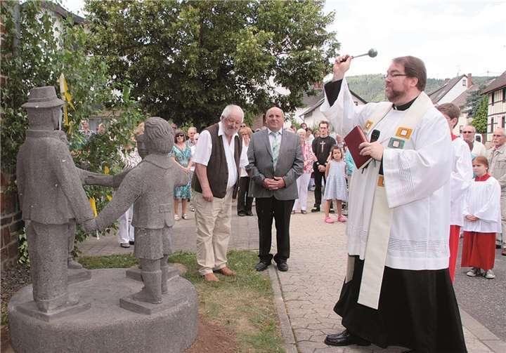 Pastor Gebhard Lück segnet die Figurengruppe. Künstler Dieter Heuft (l.) und Ortsbürgermeister Ewald Neiss schauen zu.
