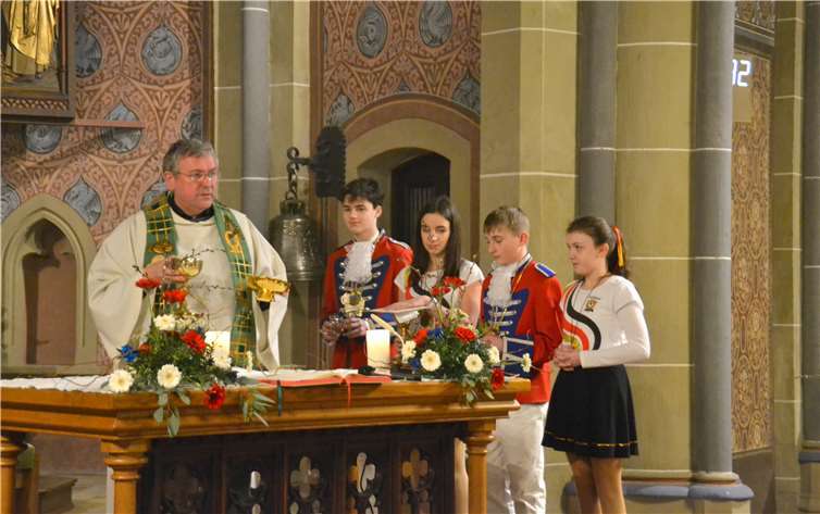 Pastor Marmann mit karnevalistisch gekleideten Messdienerinnen und Messdienern.