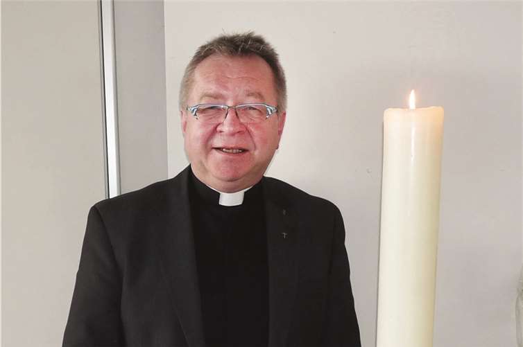 Pastor Ralf Birkenheier neben der Osterkerze von St. Cyriakus. SF