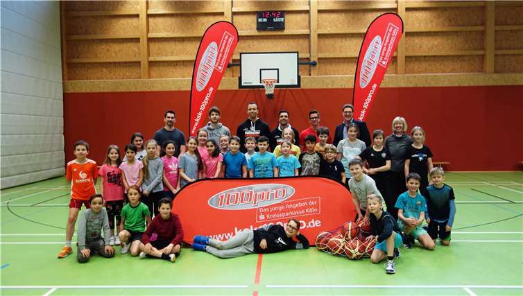 Patrick Hupperich, Filialdirektor der Kreissparkasse Köln in Meckenheim am Neuen Markt (hintere Reihe, 2.v.r.), begrüßte Schülerinnen und Schüler des Konrad-Adenauer-Gymnasiums zum 100pro-BasketballTraining mit den Dragons-Profis Anish Sharda und Bo Meister (hintere Reihe, Mitte). Foto: privat