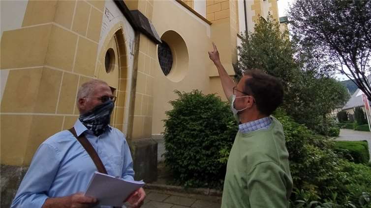Paul Radermacher (li.) und Pastor Jörg Meyrer begutachten die Probebemalung an der Nordseite von St. Laurentius. Foto: Weber