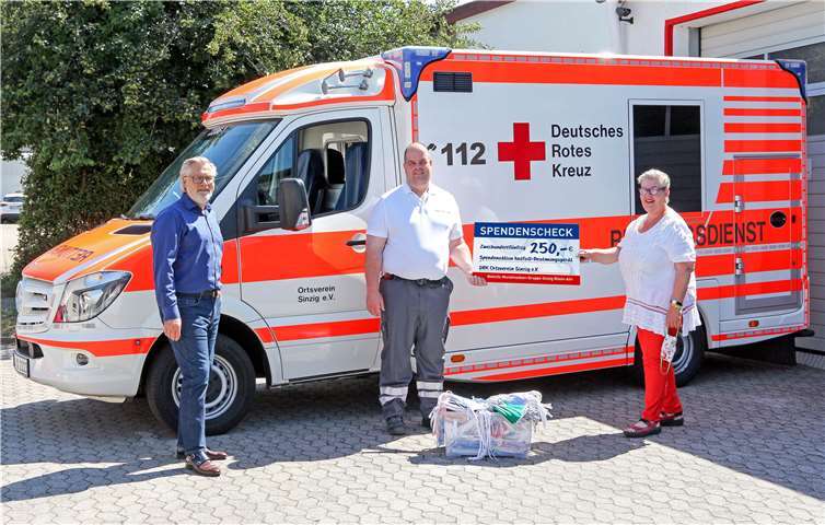 Petra Fix und Ralf Urban (li.) von der Sinziger Behelfsmaskengruppe überreichten 250 Mund-Nasen-Masken und eine Geldspende in Höhe von 250 Euro für die Beschaffung eines neuen Notfall-Beatmungsgerätes an DRK-Bereitschaftsleiter Marco Hengsberg (Mitte). Foto: Thorsten Trütgen
