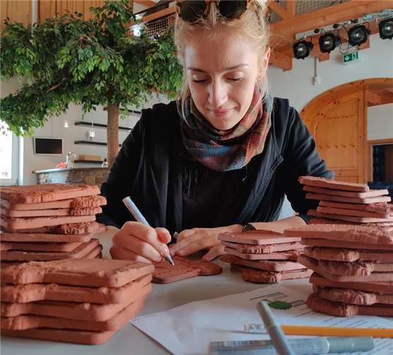 Petra Litt von der „Zweiten Heimat“ ist die Kalligrafin der Westerwald-Kinder – sie beschriftet alle Keramiken der Baumpatenschaften mit der gewünschten persönlichen Widmung. Die Patinnen und Paten sind dabei sehr kreativ. Fotos: DKSB