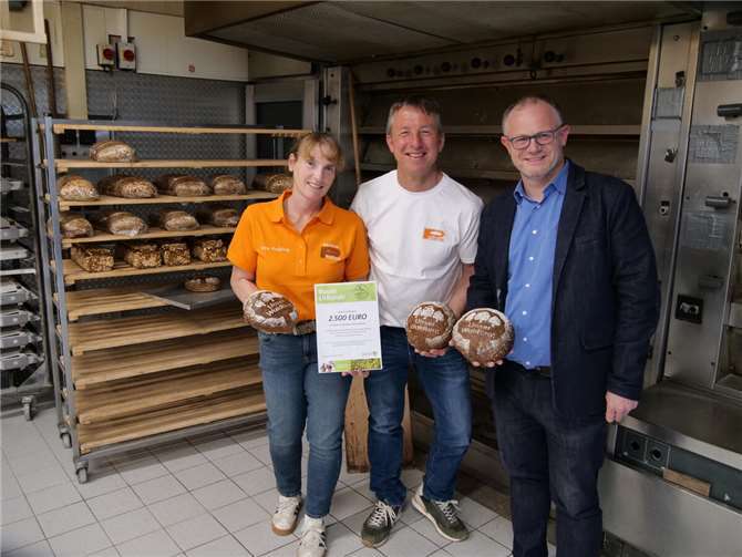Petra Preißing präsentiert Oberbürgermeister Jan Einig das beliebte Waldbrot: das Bäume versetzen kann. Für jedes verkaufte Brot spendet die Bäckerei Preißing an das Aufforstungsprojekt „Wurzeln für Alle“ der Stadtwerke Neuwied.  Foto: SWN/Dennis Steinhardt