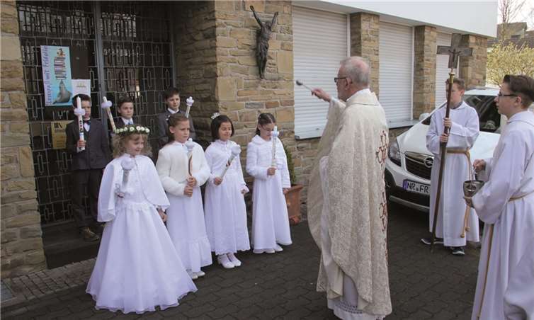 Pfarrer Klaus Theis segnet die Kommunionkinder vor dem Pfarrheim. STUHA