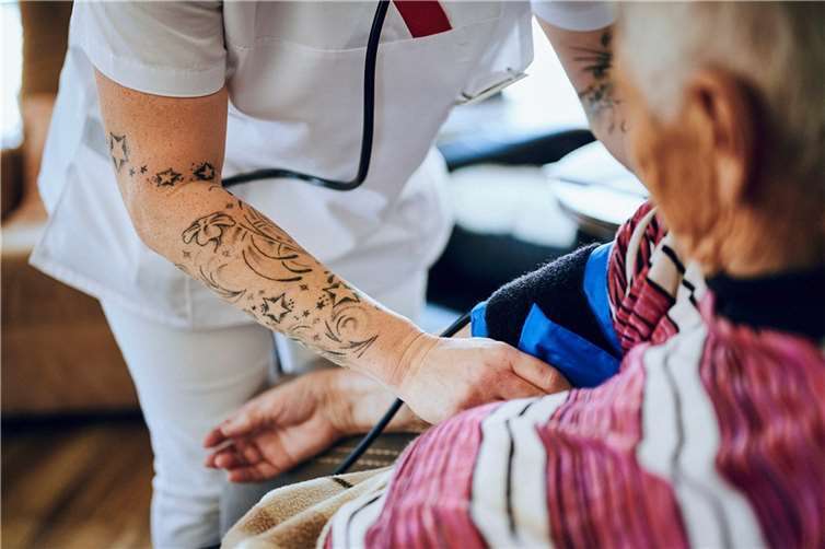 Pflegekraft beim Blutdruckmessen.  Foto: Martin Bühler