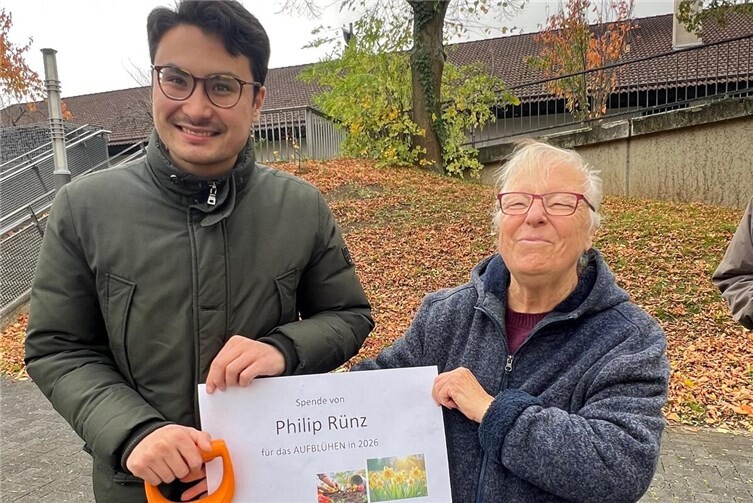 Philip Rünz übergibt Ortsringvorsitzende Roswitha Jung die Spende für Osterglockenzwiebeln und packt bei der Pflanzaktion des Ortsrings Karthause mit an. Foto: Sandra Hürter