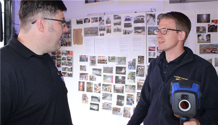 Pierre Sebastian (r.) und Christian Schrading mit der neuen Wärmebildkamera vor der FFW-Chronik.