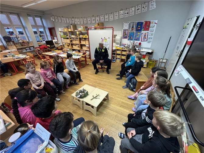 Polizeihauptkommissar Olaf Krüger erklärt den Erstklässlern im Theorieteil, wie sie sicher die Straße überqueren. Die Kinder hören gespannt zu und lernen wichtige Verkehrsregeln für ihren Alltag. Fotos: privat