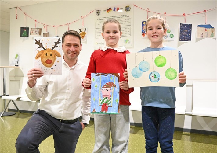 Präsentieren im Wartebereich des Bürgerservices die Motive der Weihnachtskarten-Aktion, von links: Bürgermeister Sven Schnieber, Aviana Laukart und Kira Rudolf. Es fehlt Theo Hill. Foto: Stadt Meckenheim