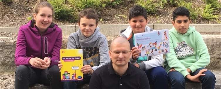 Projektleiter Alexander Sittinger und vier AG-Teilnehmern zeigen Broschüren zum Thema „Kinderrechte“. privat