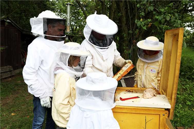 Spenden-Shuttle bringt Ahrtal in den RTL-Spendenmarathon Projektpate Dirk Steffens (l.) besucht mit den Kindern aus dem Ahrtal die Bienenstöcke. Mit der angelegten Schutzkleidung dürfen die Kinder einen Blick in die Bienenstöcke werfen. Foto: RTL / Frank Hempel