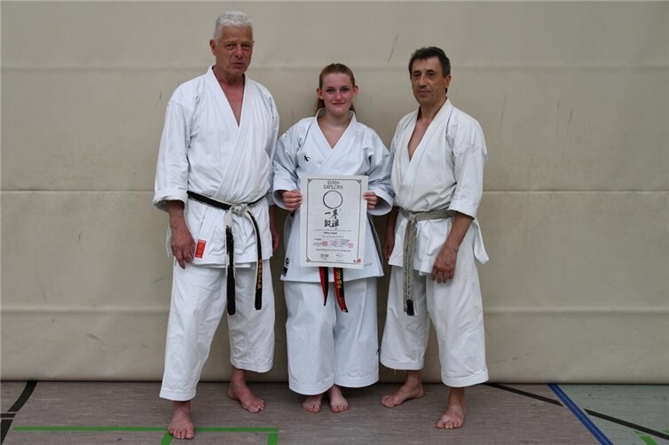 Prüfer Gunar Weichert (links) und Bundestrainer Efthimios Karamitsos (rechts) mit Helena Hoyak und der Prüfungsurkunde zum 1. DAN