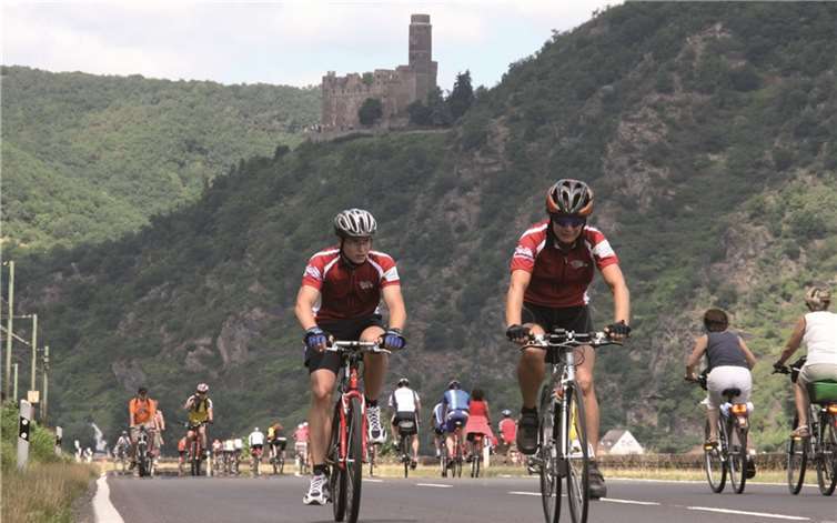 Radler ohne störende Autos vor romantischer Burgenkulisse im Mittelrheintal.Suzanne Breitbach