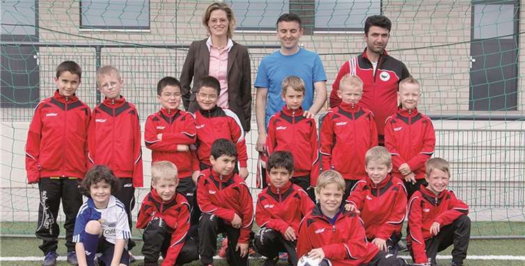 Rebecca Schenkelberg freut sich mit den Trainern und dem Team über die neuen Trainingsanzüge. privat