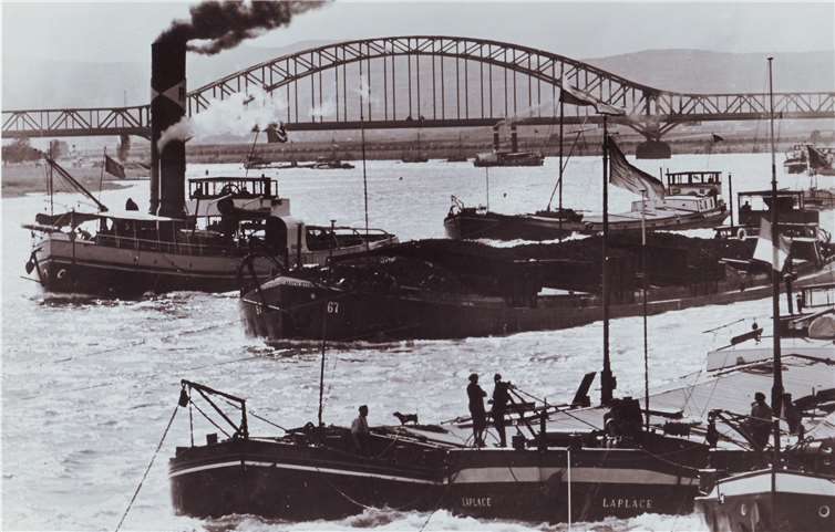 Reger Schiffsverkehr herrscht in den 1930er Jahren auf dem Rhein vor der Kulisse der Kronprinz-Wilhelm-Brücke. Ein Räderboot unterquert soeben mit seinem Schleppzug die Brücke, während ein Schraubenschlepper bereits das Engerser Ufer passiert.Sammlung Moritz