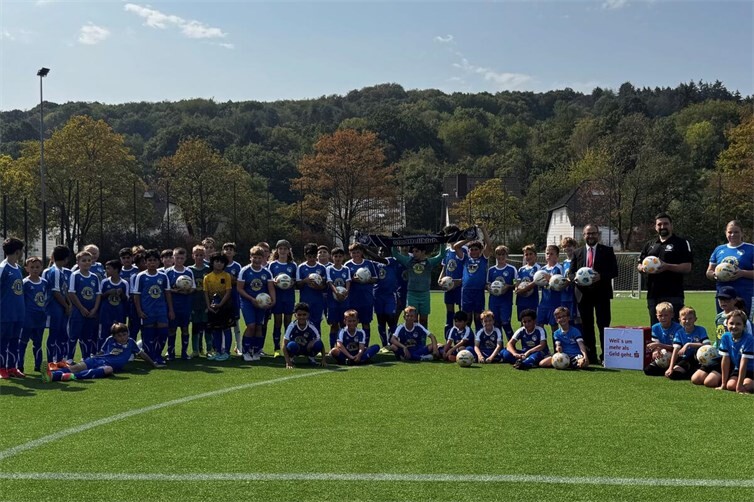 René Runkler, Leiter des BeratungsCenters Ahrweiler, und Christopher Krah, Vorstand der SG, überreichen die Fußbälle an die Nachwuchsspielerinnen und -spieler der SG Bachem/Walporzheim
