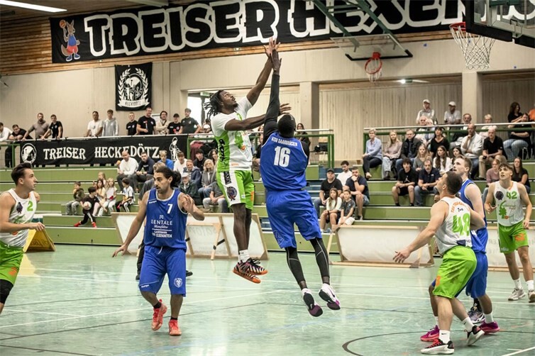 Richard Henderson vom TuS Treis-Karden (in grün-weiß beim Sprungwurf) und der Saarbrücker Papa Edouard Diouf (in blau, Nr. 16) lieferten sich starke Duelle unter den Körben. (Foto: Lisa Ferrlein).