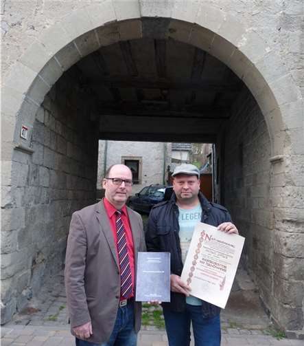 Riedens Ortsbürgermeister Andreas Doll und der Restaurator im Steinmetz- und Steinbildhauerhandwerk Michael Pitack vor dem historischen Torbogen in der Kirchstraße 39. SF