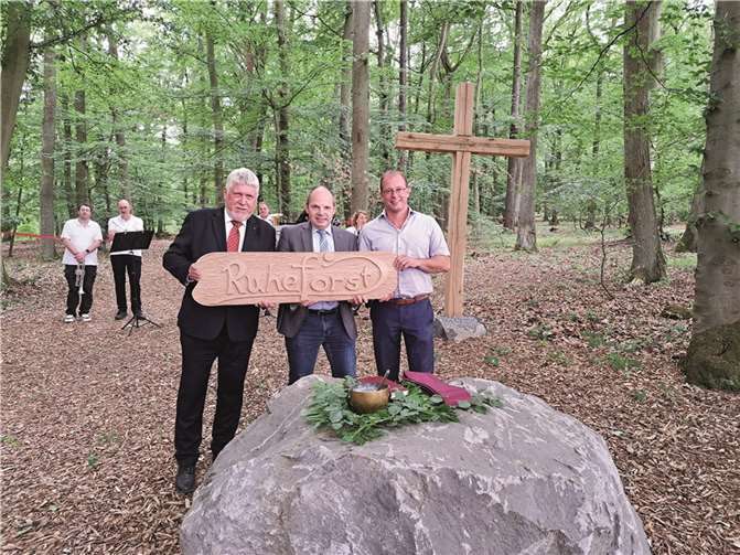 Ruheforst-Geschäftsführer Jost Arnold überreicht ein aus Holz gearbeitetes Namensschild.