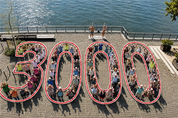 Rund 70 Teilnehmerinnen und Teilnehmer formierten sich an der Neuwieder Rheinpromenade zur Zahl „3000“ – dem Symbol der Lions-Aktion „3000 Schritte für Bewegung und Begegnung“. Das veröffentlichte Bild wurde mithilfe von Künstlicher Intelligenz (KI) grafisch überarbeitet, um die dargestellte Formation „3000“ besser sichtbar zu machen.