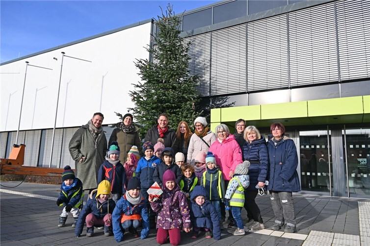 Schmückten gemeinsam den Weihnachtsbaum vor dem Rathaus: Bürgermeister Sven Schnieber (hinten 3.v.l.) mit den Kindern der beteiligten Kitas, ihren Erzieherinnen und Mitarbeitenden des Jugendamtes. Foto: Stadt Meckenheim