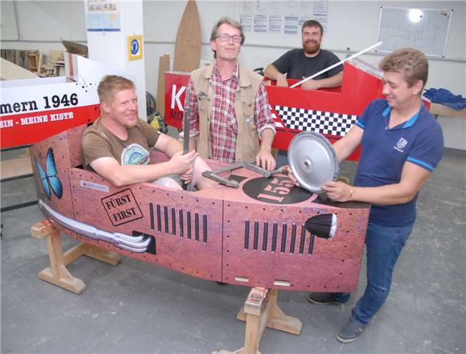 Schreinermeister Tino March (hinten) stellt mit Teilnehmern in der Werkstatt die Seifenkisten für das Rennwochenende her.