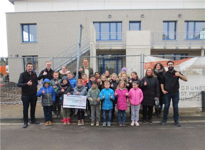 Schüler der Grundschule St. Peter und Paul und Mitarbeiter des REWE Marktes Azhari vor dem Neubau der Grundschule.privat