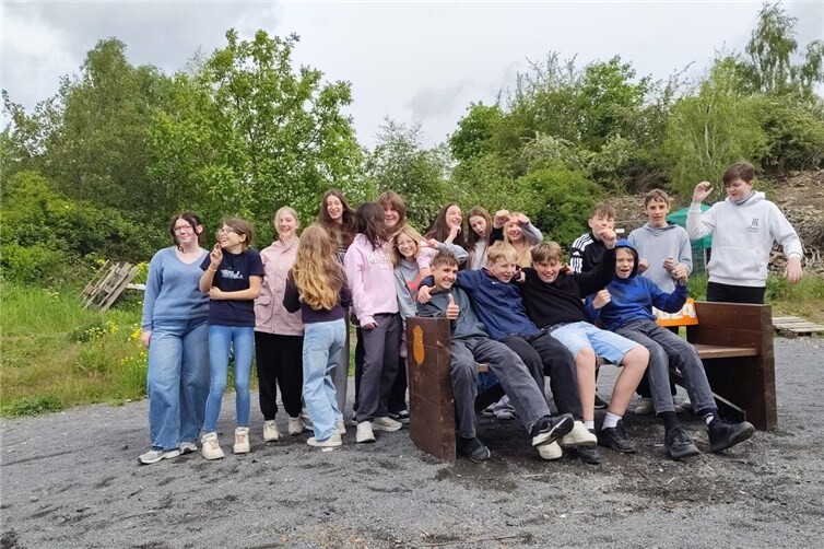 Schüler der siebten Klasse versammeln sich an der Bank, die von Obi in Mayen der Schule gespendet wurde, um sich danach an die Arbeiten am Schulhof zu begeben.