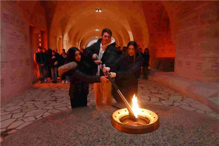 Schüler entzünden im Beinhaus die Flamme des unbekannten Soldaten.