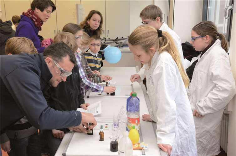 SchülerInnen des Gymnasiums betreuen Besucher bei der Durchführung naturwissenschaftlicher Versuche.privat