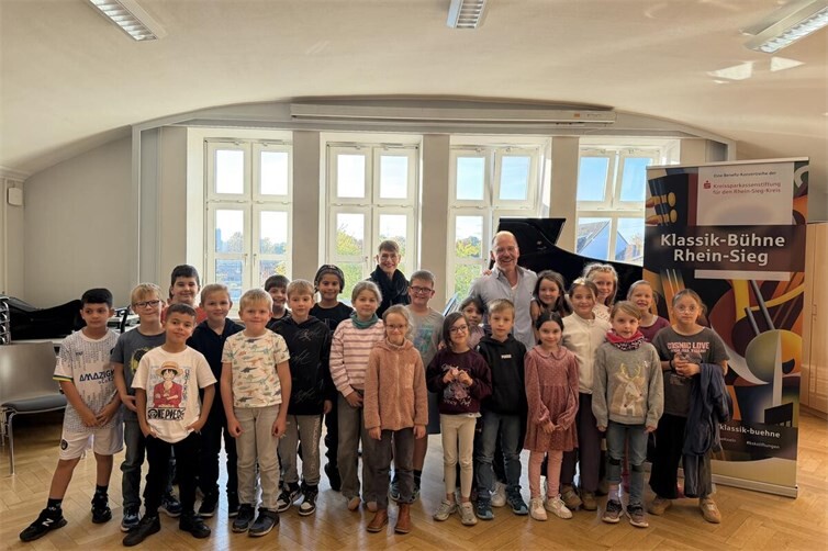 Schülerinnen und Schüler der Klassen 3a, 3b und 3c der KGS Meckenheim mit Pianist Markus Kreul und Kirsten Felgner von der Kreissparkassenstiftung für den Rhein-Sieg-Kreis nach dem musikalischen Erlebnis „Zauberkasten Klavier“