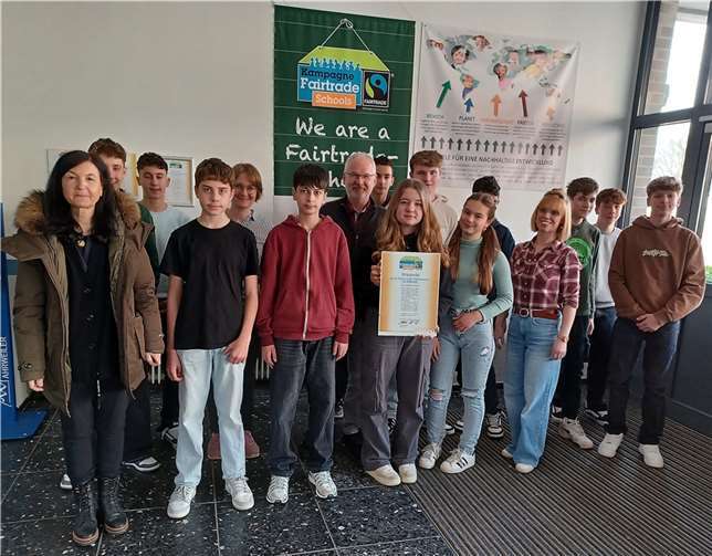 Schülerinnen und Schüler des 8. Schuljahres, die das Thema Fairtrade mit ihren Lehrerinnen Katharina Müller (hinten Mitte) und Julia Selbach (vorne rechts) im Englischunterricht am Beispiel fair produzierter Kleidung behandelt haben, mit Schulleiterin Christa Killmaier-Heimermann (links) und Bernhard J. Müller, dem Leiter der Eine-Welt-Aktivitäten am EKG.  Foto: Martina Müller