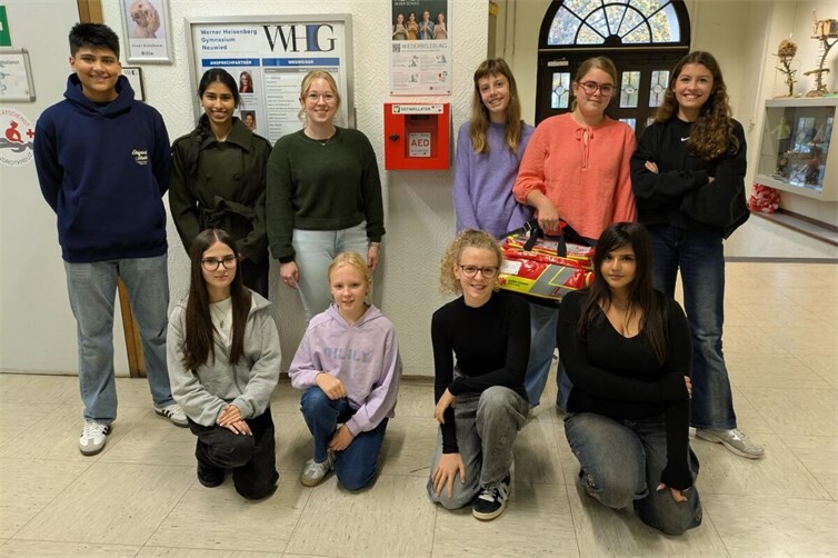 Schülerinnen und Schüler des Schulsanitätsdiensts am WHG mit Lehrerin Tina Prämaßing (3. von links, hintere Reihe) vor dem neuen AED