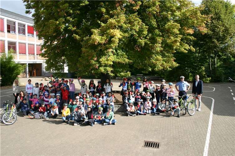 Schulleiterin Sandra Müller (hi.l.), die Kinder der Klassen 4a, 4b (Leitung Bianca Georg, 2.v.l., kniend) und 4c (Leitung Pia Burth, 4.v.l.), Polizeihauptkommissar Volker Frink und Peter Mohr (hi.r.). Foto: Sparkasse Westerwald-Sieg