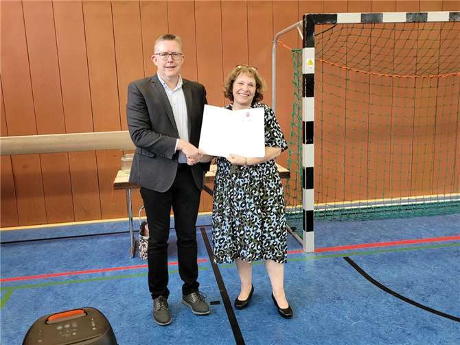 Schulrat René Schermuly vom ADD Koblenz überreicht Sabine Stahlberg die Entlassungsurkunde. Mit Ende des Schuljahres geht die Schulleiterin der Grundschule im Buchfinkenland in Pension.  Foto: VG Montabaur, Viola Marschall