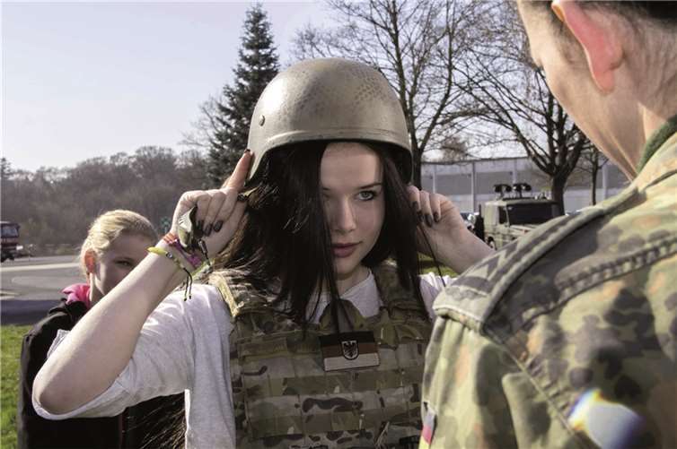 Schwer zu tragen: Constance probiert Helm und Schutzweste der Soldaten an.