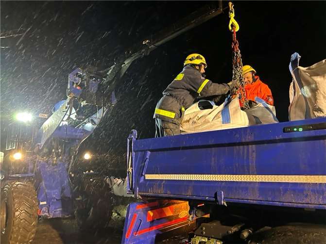 Schwerstarbeit bei Dauerregen und heftigem Wind. THW-Einsatzkräfte verladen große Säcke mit Sand, um Einsatzstellen zu sichern.  Foto: THW/Nina Levien