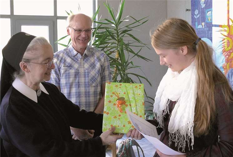 Schwester Anneclaire Gerharz (Schul-Leiterin) und Dr. Wenndorf gratulieren der Schul-Siegerin Michelle Schäfer zu ihrem Sieg im Geografie-Wettbewerb„Diercke WISSEN“.