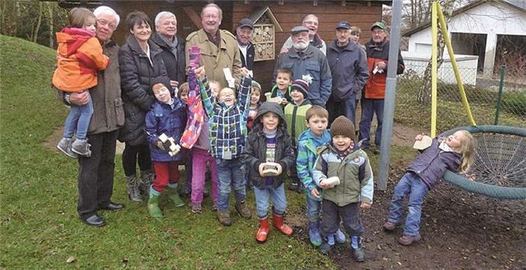 Senioren, Erzieherinnen und Kinder im Kindergarten vor dem selbst gebastelten Insektenhotel. privat
