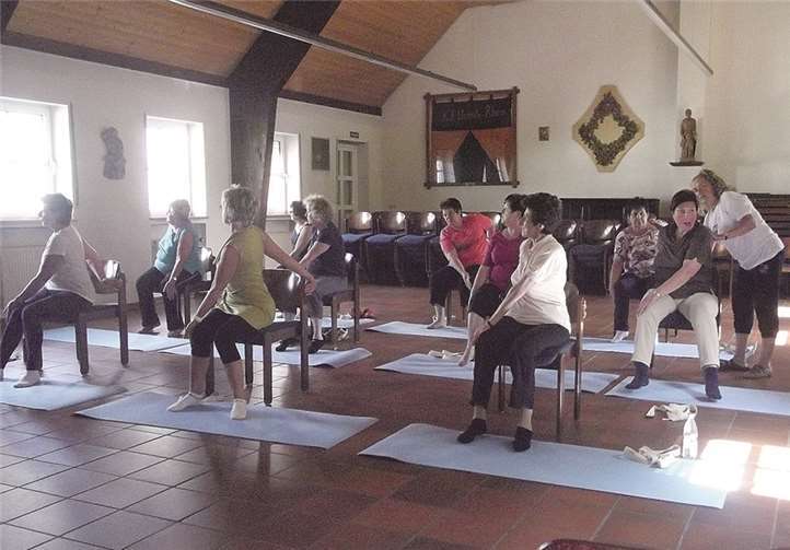 Seniorenyogagruppe bei ihren Drehsitzübungen auf dem Stuhl zur Stärkung des Lendenwirbelbereichs.  Privat