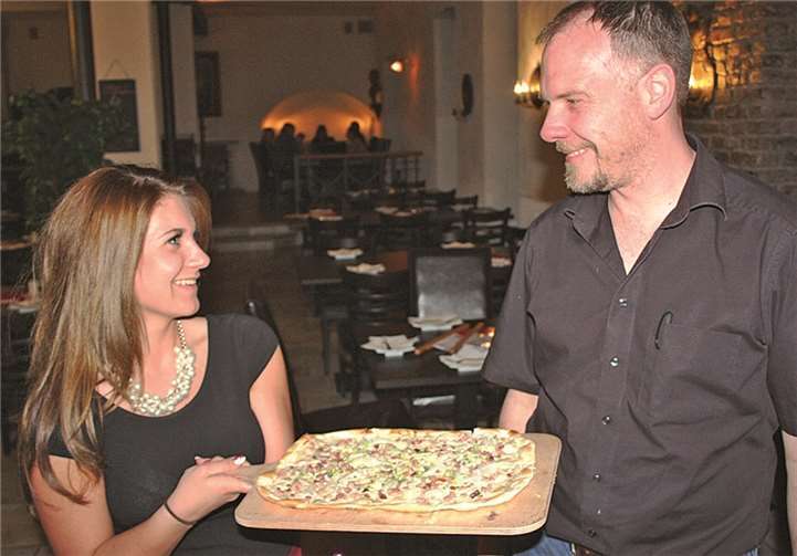 Servicekraft Laura Stapler und Restaurantchef Andreas Bieker mit einem von 42 unterschiedlichen Flammkuchen. FF